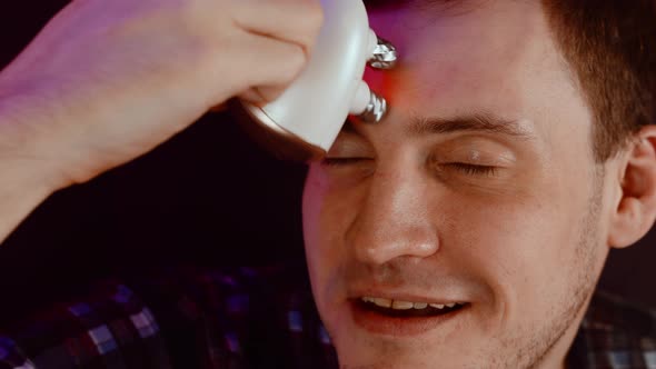 Young Man Using 3d Massager for Face