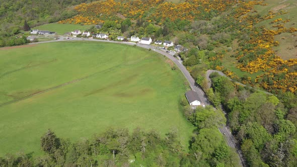 Aerial drone view of countryside in Scotland, with a little village in the gr