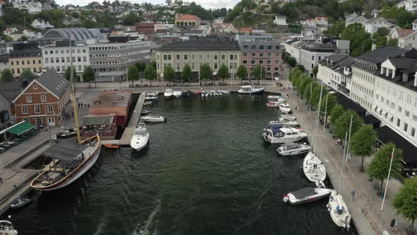 Sailboats And Yachts Anchored On The Pier With The Seaside Town Of Arendal, Norway.  - aerial drone