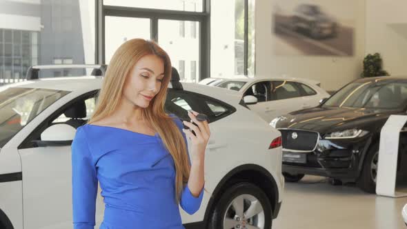 Beautiful Happy Woman Holding Car Key To Her New Automobile at the Dealership