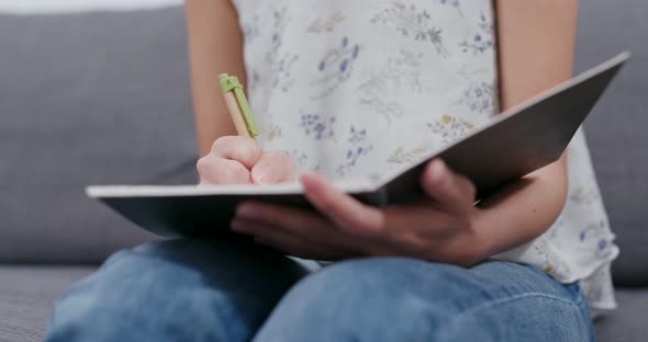 Woman take note on notebook at home