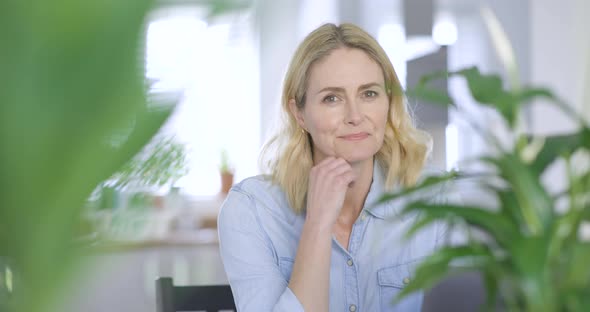 Smiling businesswoman looking at camera with hand on chin