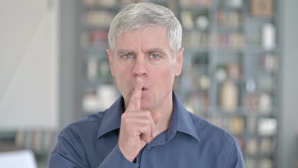 Portrait of Middle Aged Man Asking To Be Quiet By Putting Finger on Lips