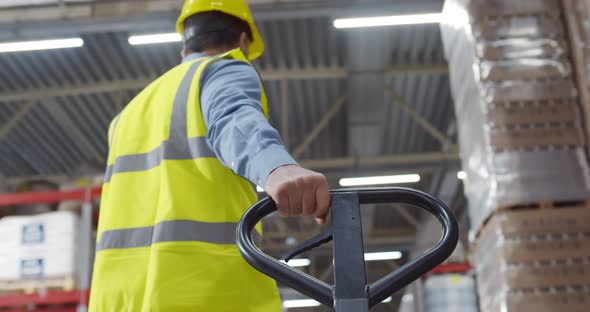 Senior Worker in Warehouse Using Hand Pallet Stacker to Transport Goods