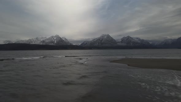 Cold winter conditions of the arctic, snow-covered Lyngen Alps on horizon, drone