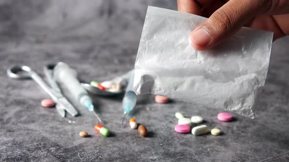 Drug Addiction Concept with Hand Holding Heroine Packet on Black Backgrund