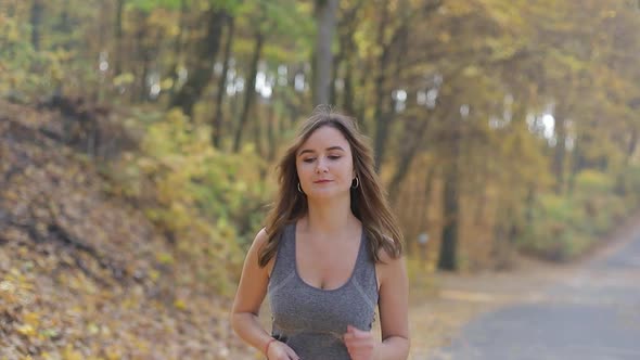 Young woman runner, in autumn Park. Fitness woman working out outdoors.