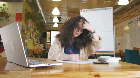 Young Happy Woman Working in the Office Writing Something and Using Computer