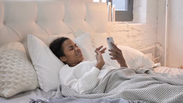 Young African Girl Using Smartphone While Laying in Bed