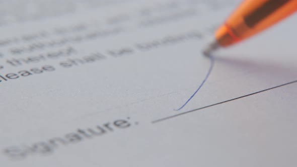 Closeup of a Focused Young Businessman Puts His Signature on a Paper