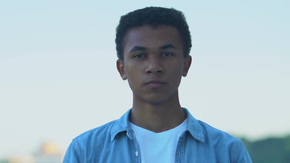 Pensive African-American teenager boy touching chin