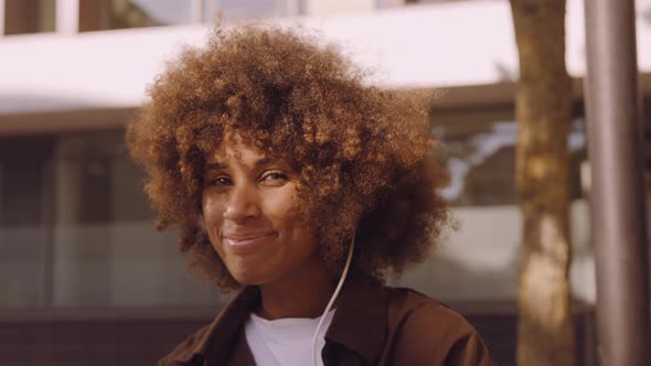 Woman Smiling As She Listens To Music From Headphones