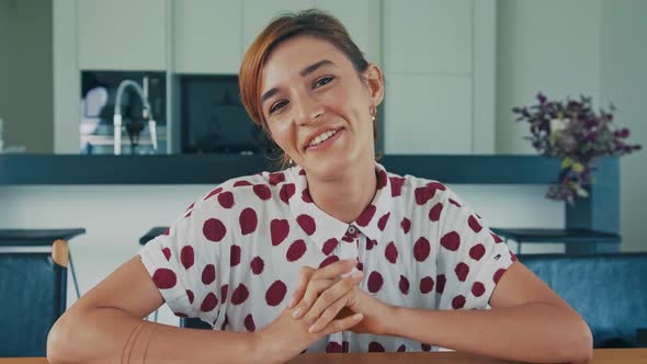 Young Woman Sitting on Kitchen Looking at Camera Having Talk Using Laptop Webcam