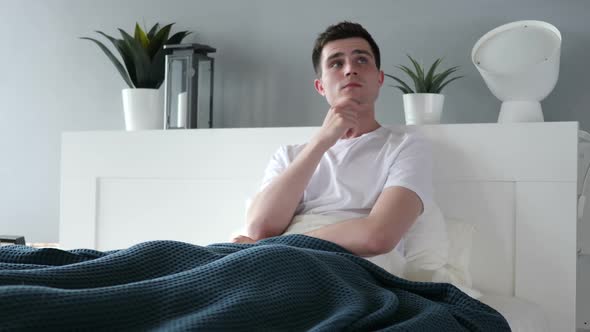 Pensive Man Thinking While Sitting in Bed