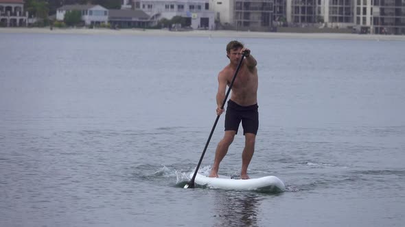 A man paddles his SUP stand-up paddleboard in a lake
