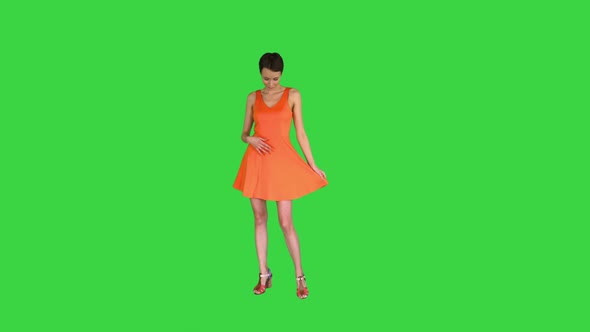 A Beautiful, Cheerful Woman Straightens Her Dress on a Green Screen, Chroma Key.