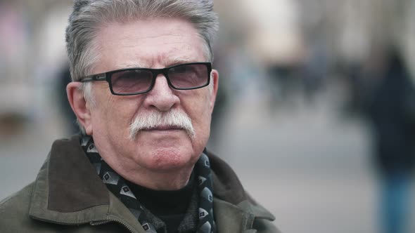 White-haired Man in Black Sunglasses Smiling and Standing in a Street