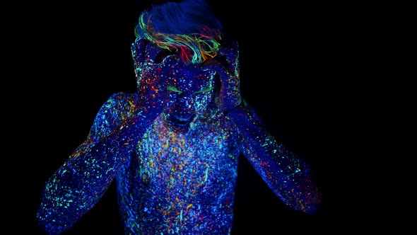 Man with Headache From an Overdose is Standing in Dark Studio Painted with Fluorescent Paints and