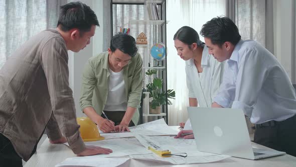 Group Of Asian Engineers Drawing Building Construction At The Office