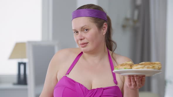 Portrait of Young Plussize Woman Choosing Unhealthy Burgers Holding Plates with Sandwiches and