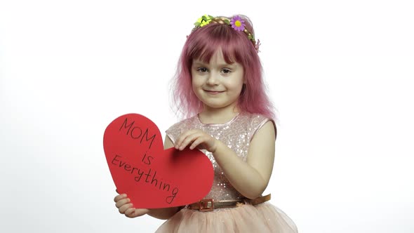 Child Girl Princess Holds Red Paper Heart with Text About Mother. Mother's Day