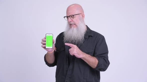 Sad Mature Bald Bearded Man Showing Phone and Giving Thumbs Down