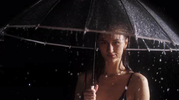 Young Woman in Black Swimming Suit Standing Under the Rain  Holding and Twirling an Umbrella