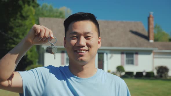 Portrait of a Young Asian Man with a House Key in His Hand. Looking at the Camera Against the