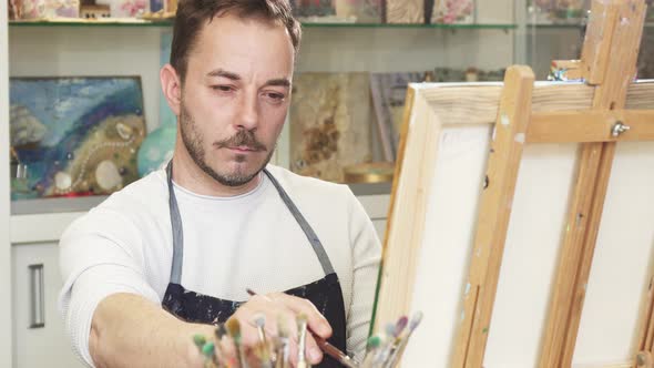 Mature Male Artist Working on a Painting at His Art Studio