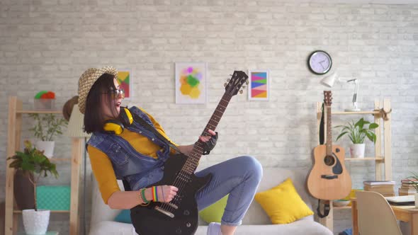 Young Woman Rocker Emotionally Playing Electric Guitar Playing Hard in Modern Apartment