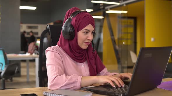 Islamic business woman in hijab with headphones and microphone are working in the office.