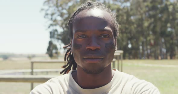 Portrait of confident african american male soldier with dreadlocks and eye black in field