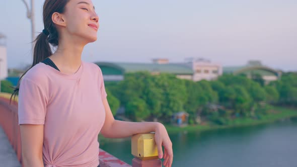 Asian young sport woman take deep breath while walking in public park.