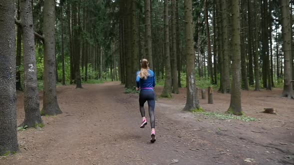 An athlete with a sports figure jogging along a forest road.