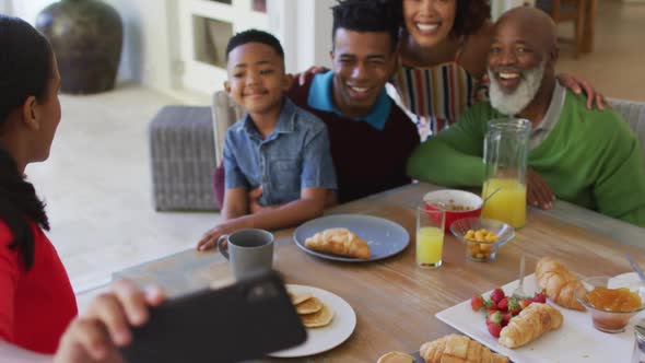 African american girl taking a selfie while having breakfast with her family at home