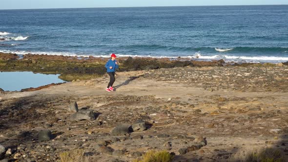 Woman Runs Along the Stony Shore of the Ocean