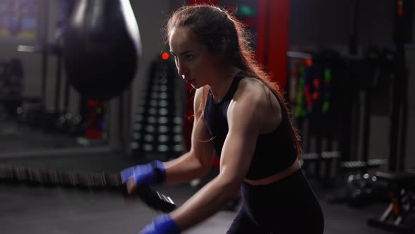 Female Boxer Doing Some Crossfit Exercises with a Rope Indoor Side View