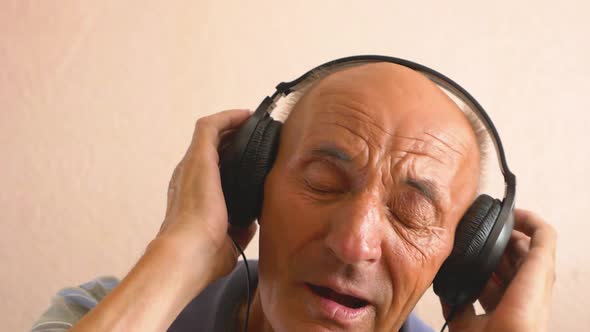 Portrait of a Caucasian senior citizen listening to music with headphones. A man over 70 is dancing