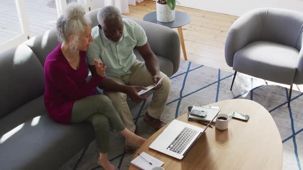 Mixed race senior couple discussing finances together in the living room at home