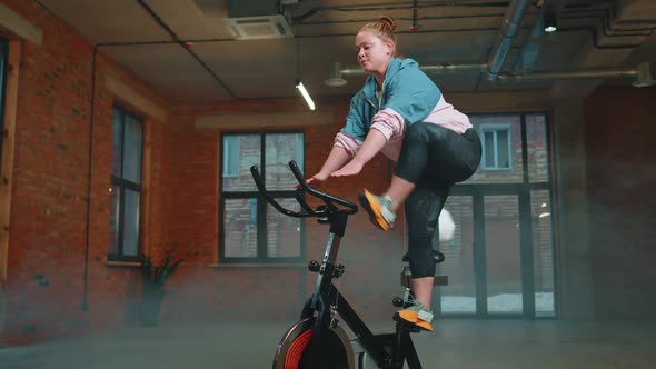 Woman Performs Aerobic Endurance Training Workout Cardio Routine on the Simulators Cycle Training