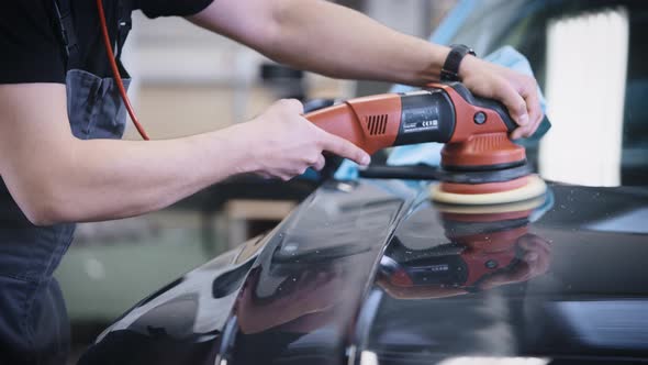 An Unrecognizable Man Polishes the Surface of a Car Using a Mechanical Polishing Machine