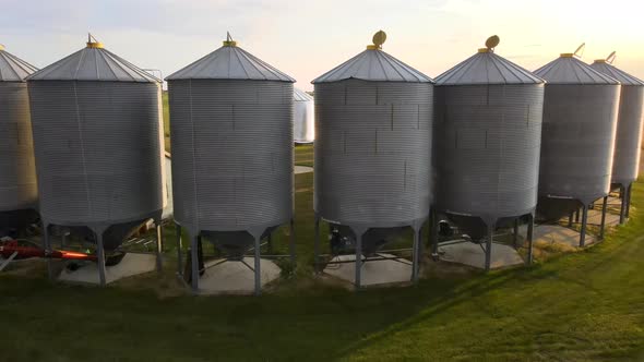 4k drone orbiting around several big grain bins standing in a half circle on small family operated f