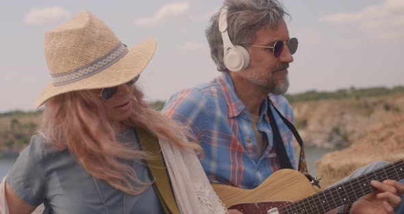 Man and Woman Play Guitars on a Meadow