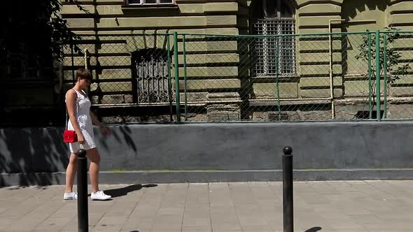 Beautiful Woman Smiling at Camera Enjoying Urban City Lifestyle. Young Funny Girl in a White Dress