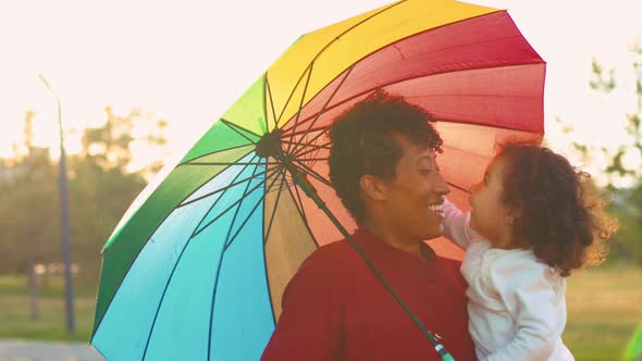 Mixed Race Family Covering From the Sun Under the Bright Umbrella