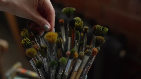 Closeup Hands of Unrecognizable Female Artist Choosing Paintbrush for Drawing Paint in Modern Dark