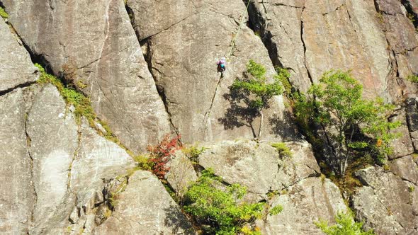 Aerial footage Rising up past young female climber and her instructor on cliff in Maine