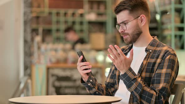 Upset Man Having Loss on Smartphone in Cafe 