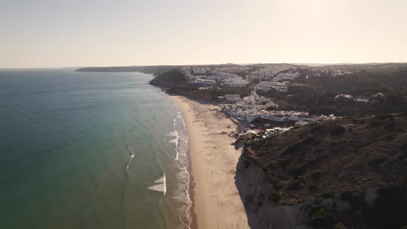Paradisiac long strip of sand and calming ocean waves, Salema beach, Algarve, Aerial view