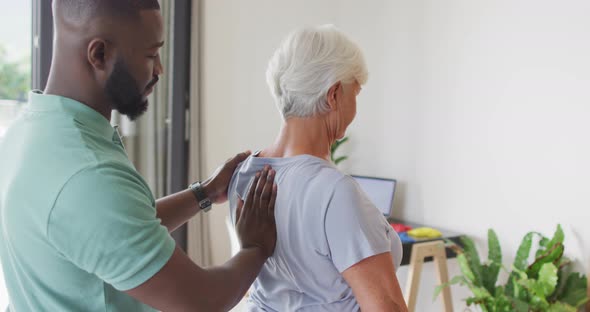 Video of african american male physiotherapist examining caucasian senior woman